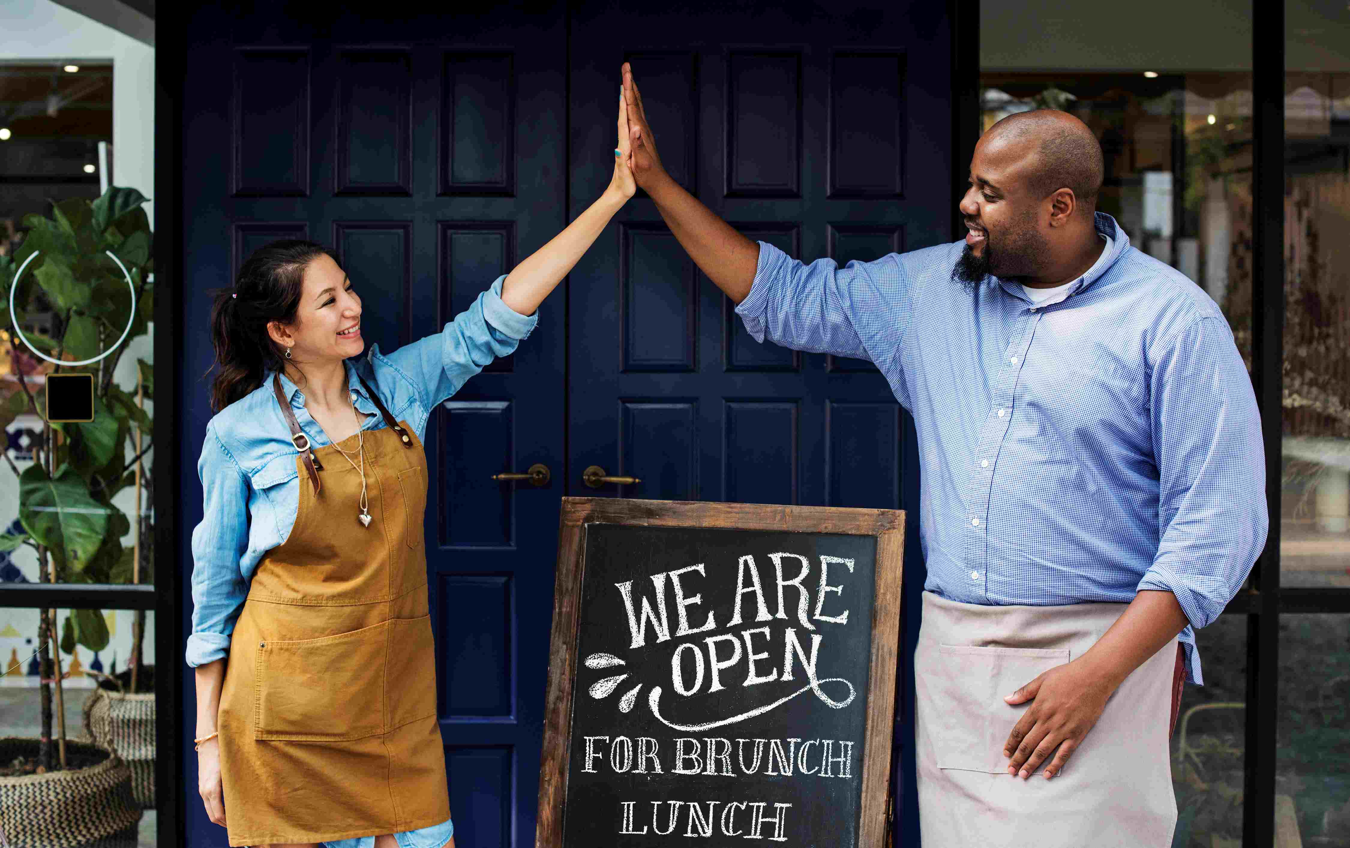 Two small business owners celebrating their grand opening with a high five